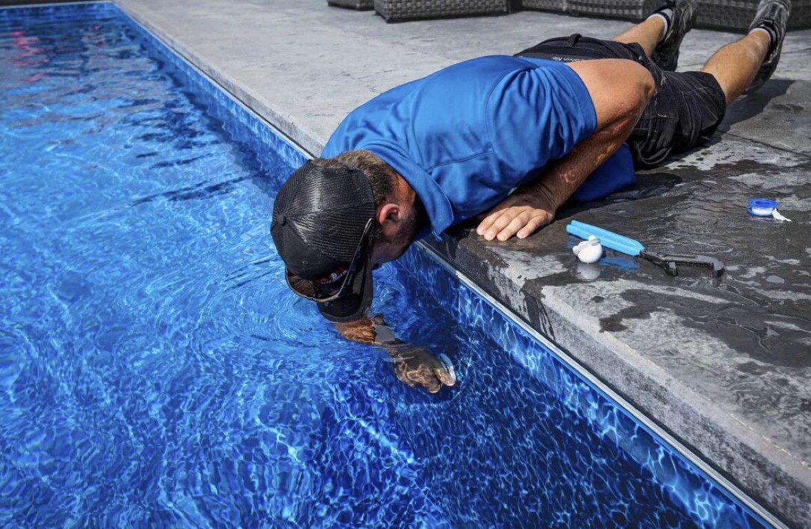 Pool technician cleaning tile and removing calcium buildup